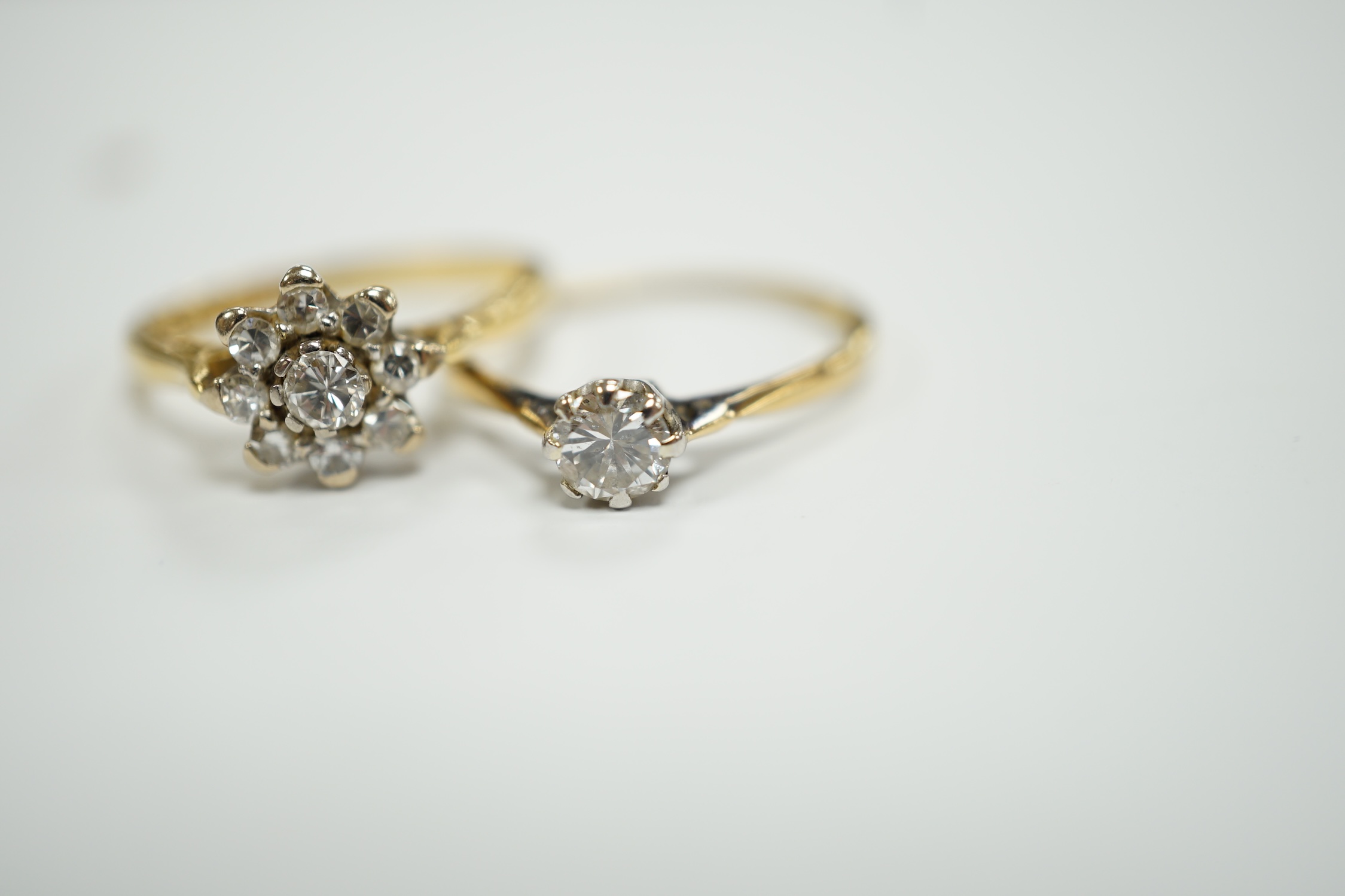 An 18ct gold and diamond cluster set flower head cluster ring, size K and an 18ct, plat. and solitaire diamond set ring, size L, gross weight 4.3 grams.